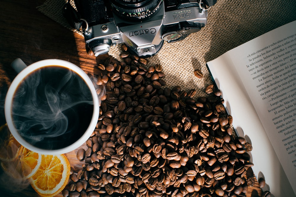 a cup of coffee next to a book and a camera