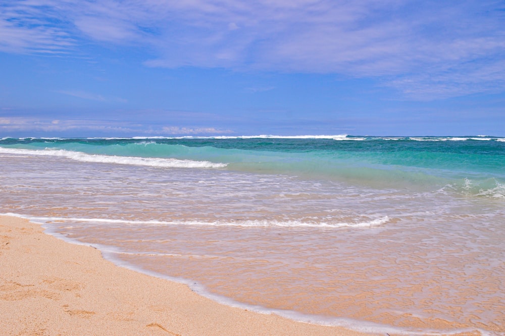 a sandy beach with waves coming in and out of the water