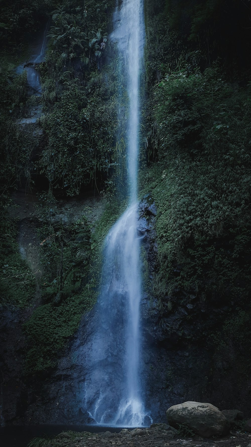 a waterfall with a large rock in front of it