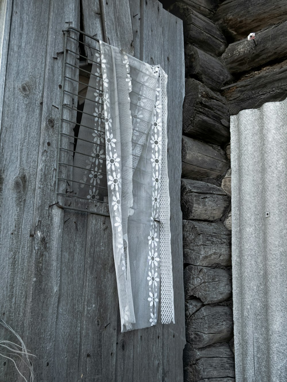 an old wooden building with a window and a curtain