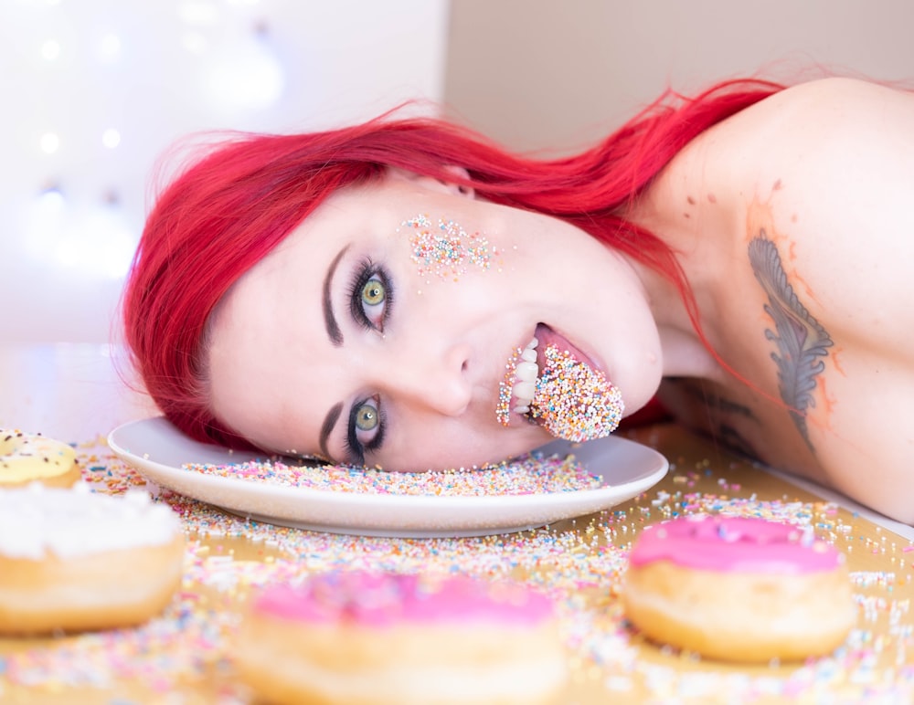 a woman with red hair eating a plate of doughnuts