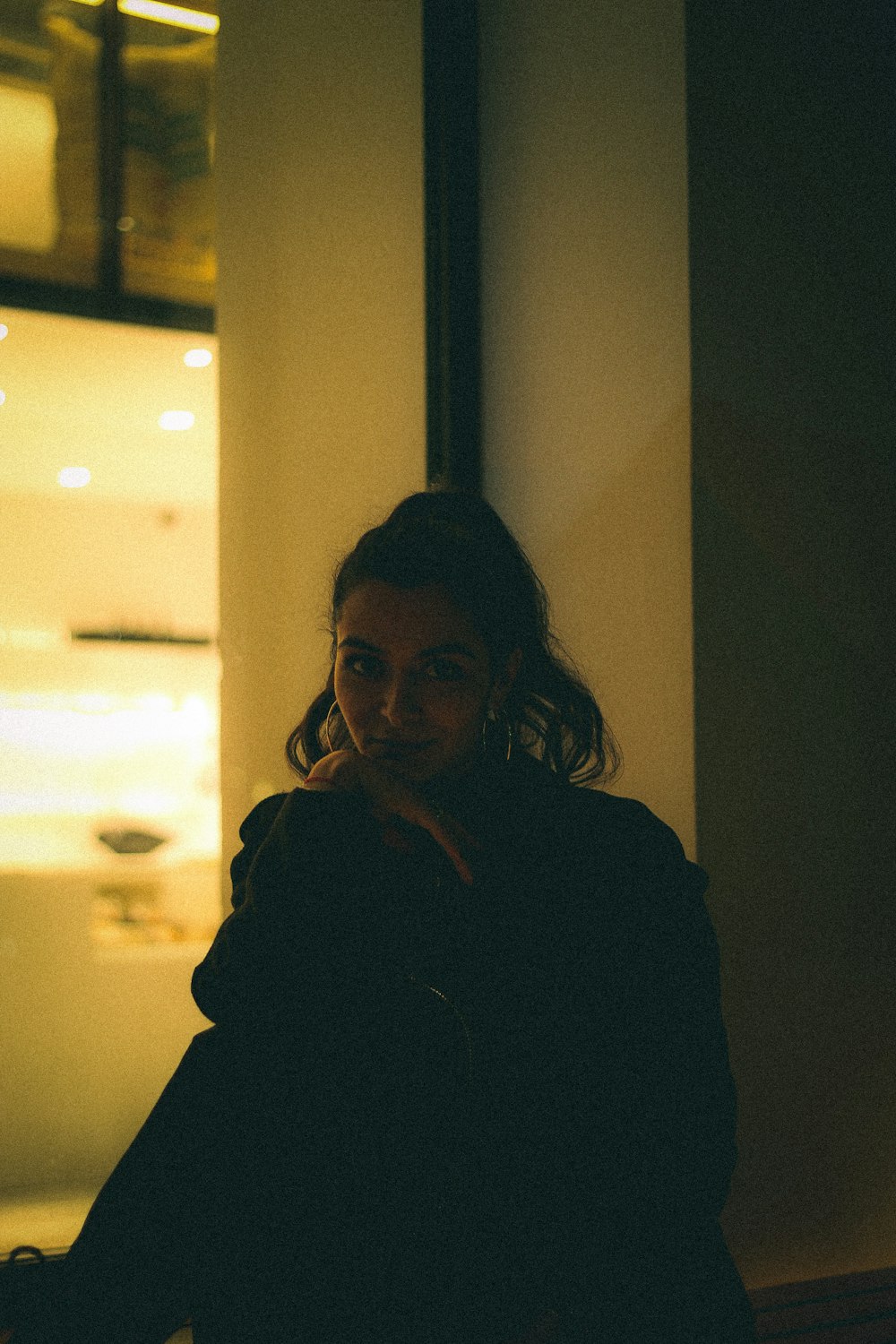 a woman leaning against a wall in a dark room