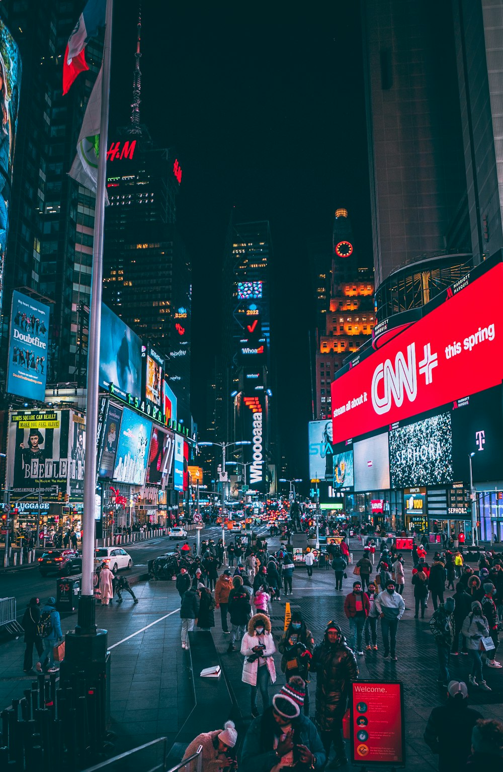 a crowd of people walking around a city at night