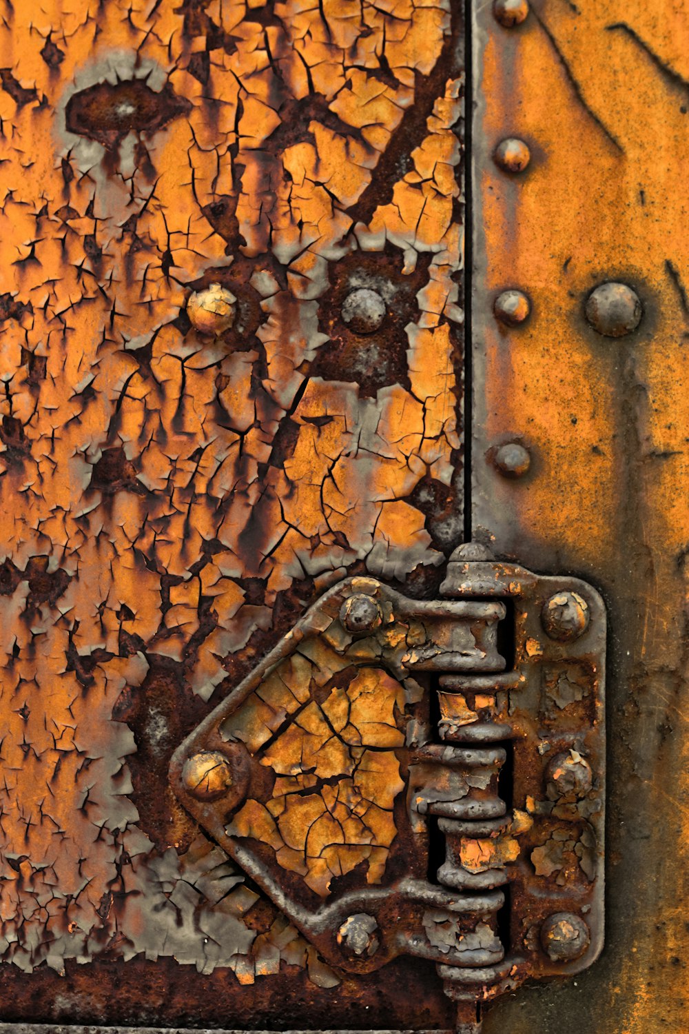 a close up of a rusted metal door with rivets