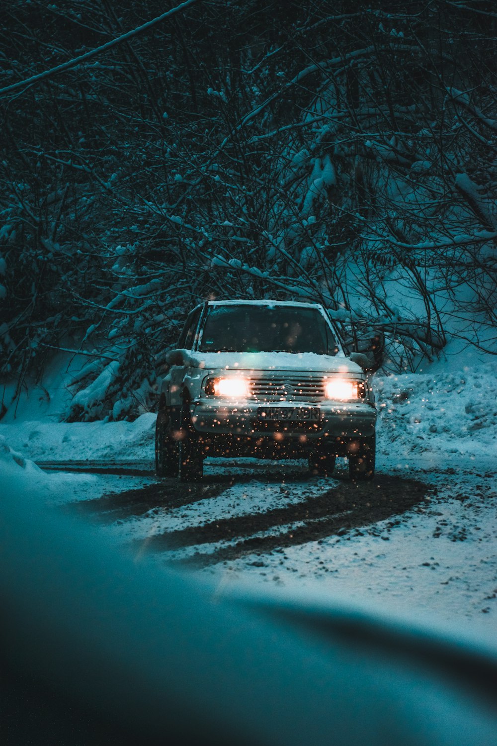 a car driving down a snowy road at night