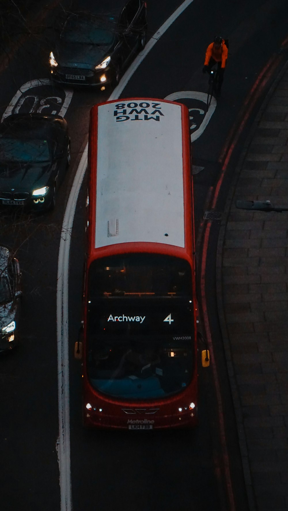 a red and white double decker bus driving down a street