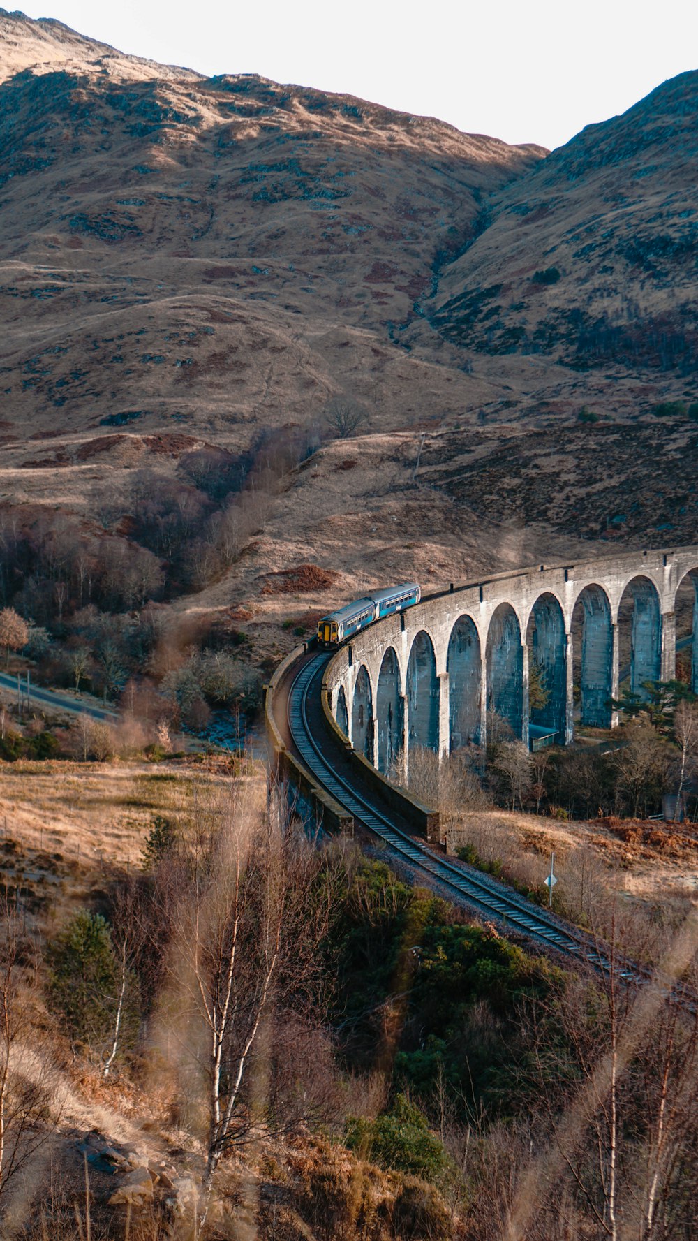 a train traveling over a bridge in the mountains