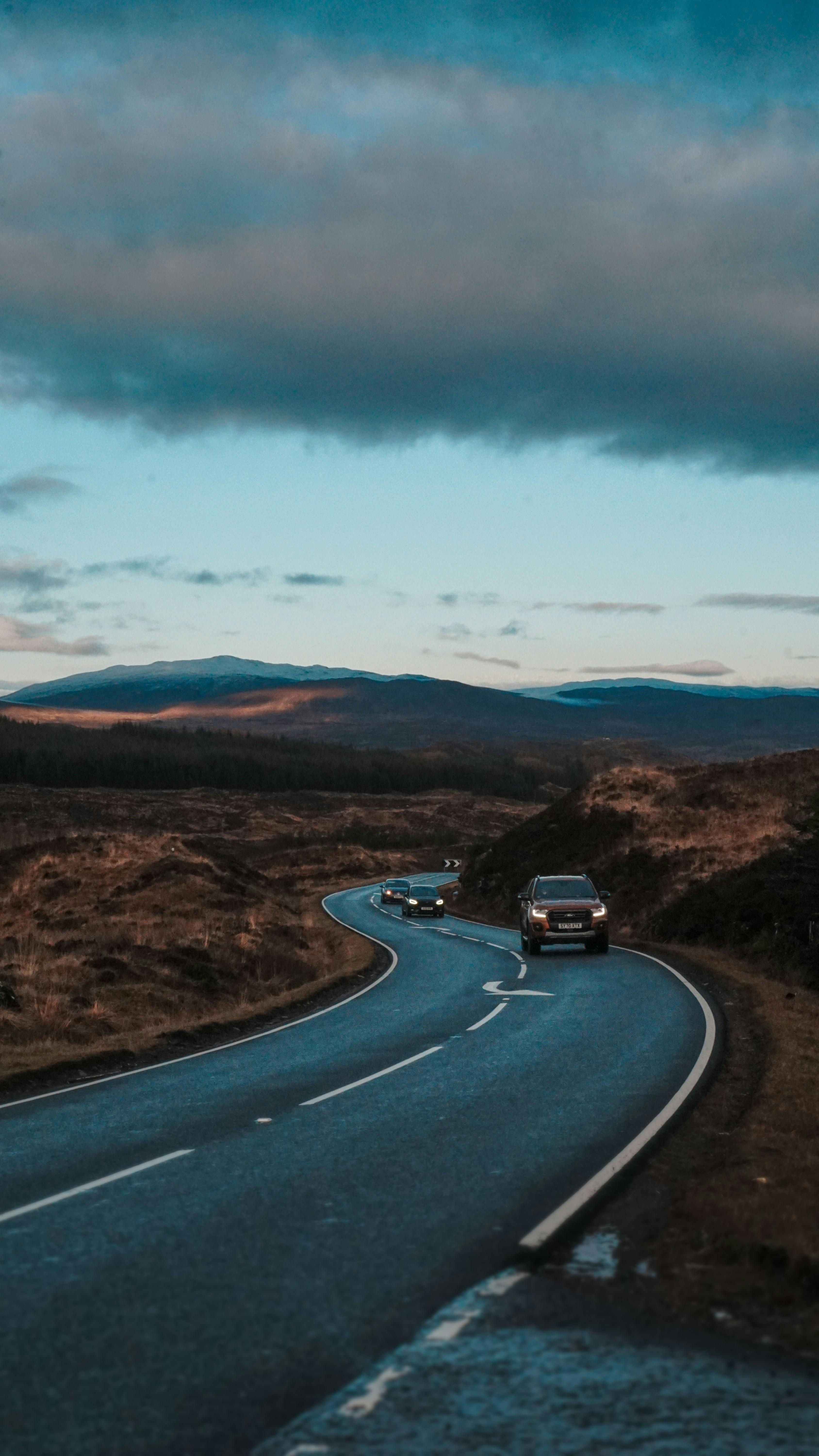 a car driving down a road with mountains in the background