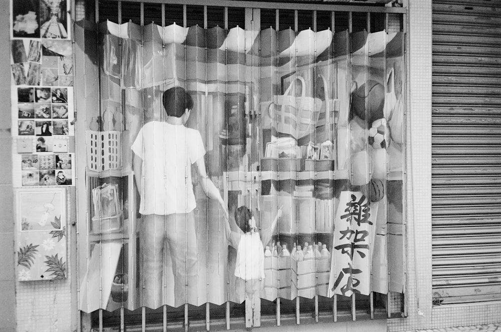 a black and white photo of a man and a child in front of a store