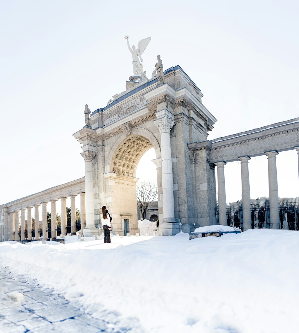 a woman standing in front of an arch in the snow