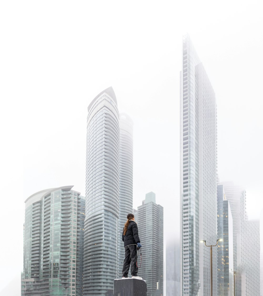 a man standing on top of a cement block in front of tall buildings