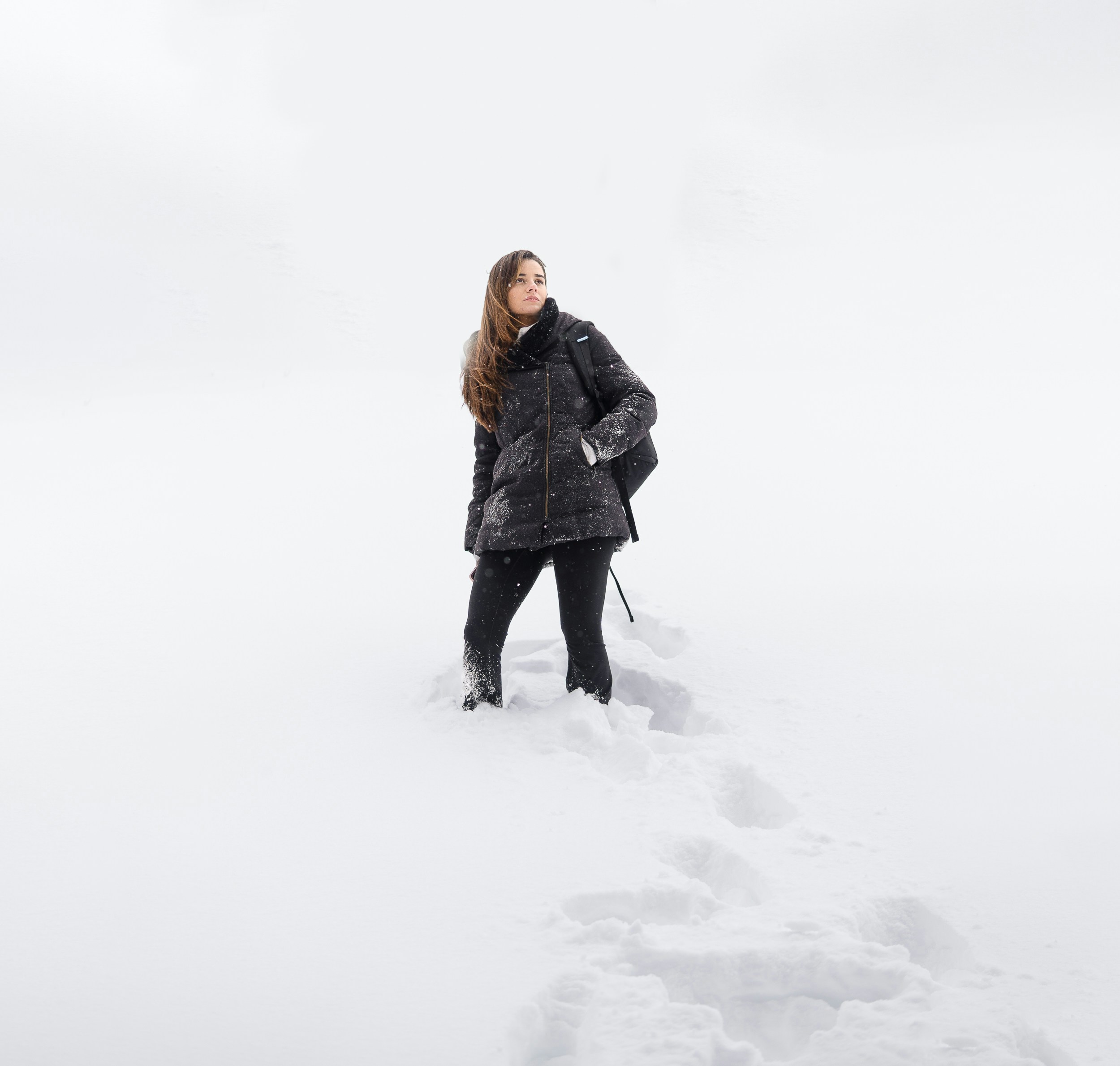 a woman standing in the snow looking up at the sky