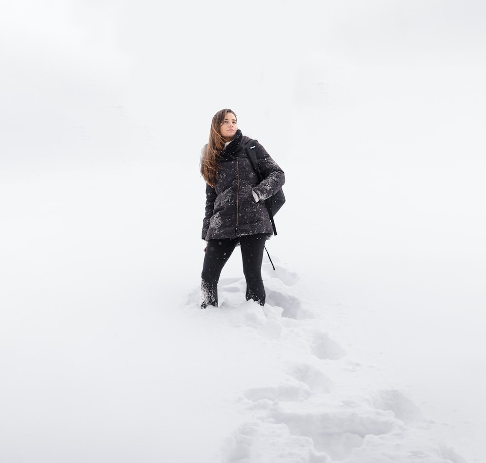 a woman standing in the snow looking up at the sky