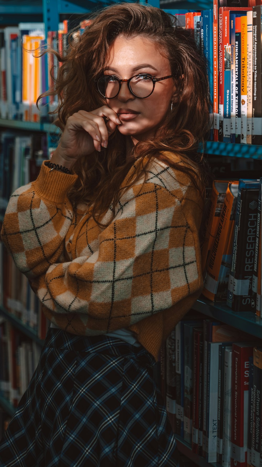 a woman in a library leaning on a book shelf
