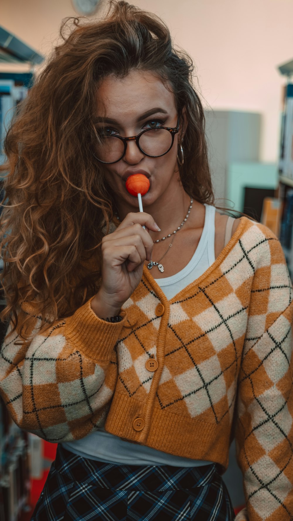 a woman with glasses holding a lollipop in her mouth