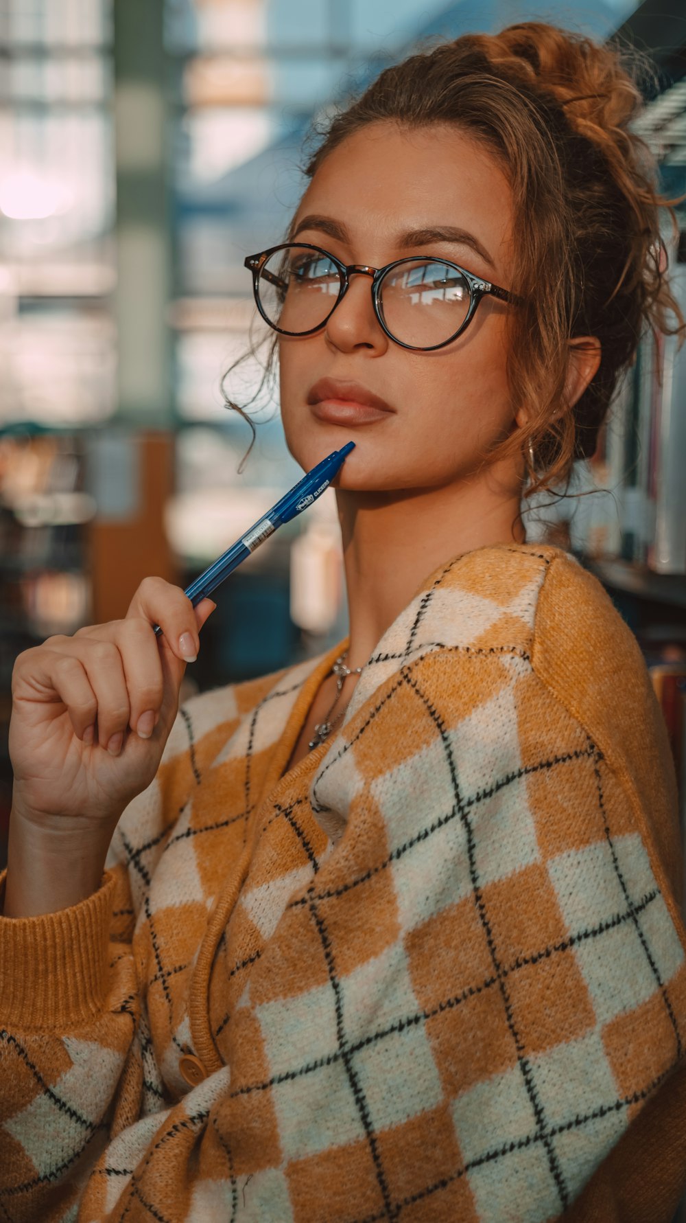 a woman with glasses holding a toothbrush in her mouth