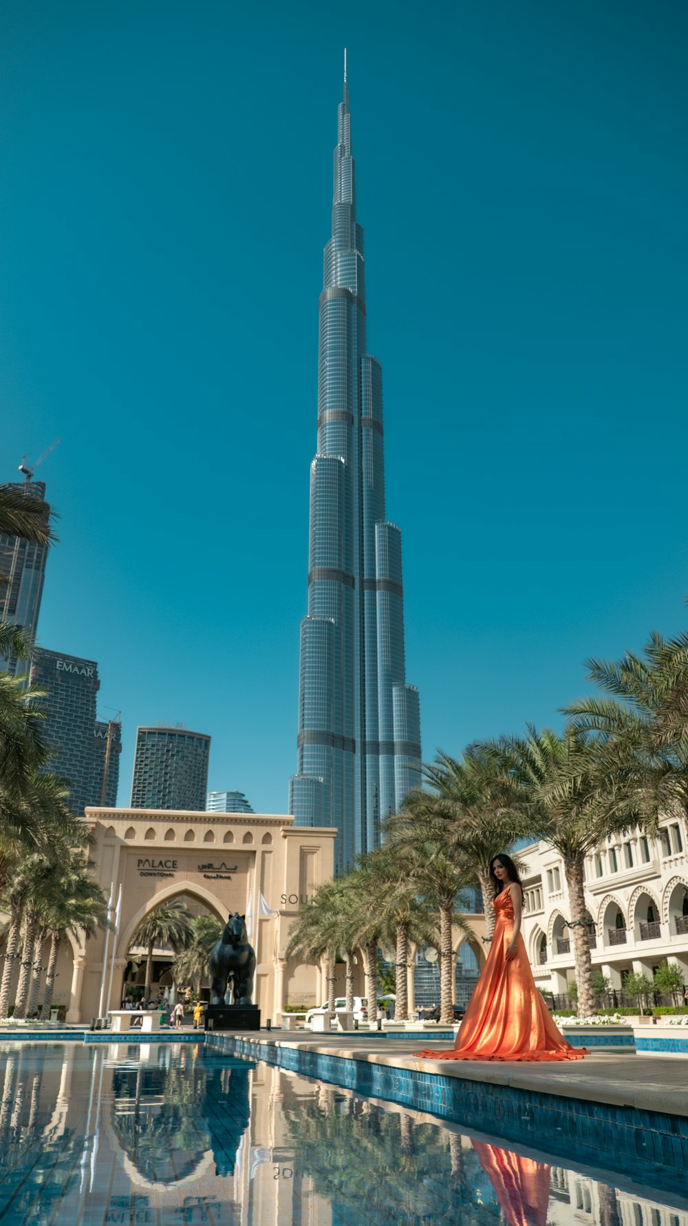 a woman standing in front of a pool in front of a tall building