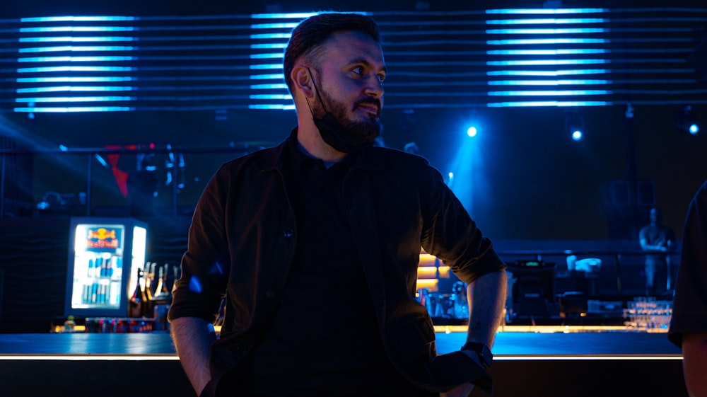 a man with a beard standing in front of a bar