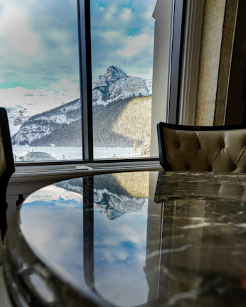 Marble coffee table reflecting the warm glow from floor-to-ceiling windows.