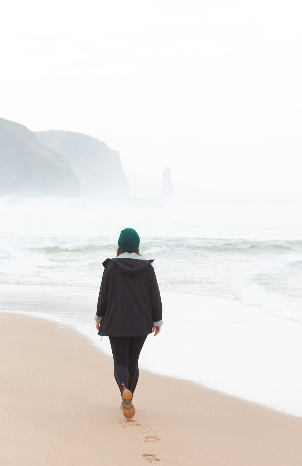 a person walking on a beach near the ocean