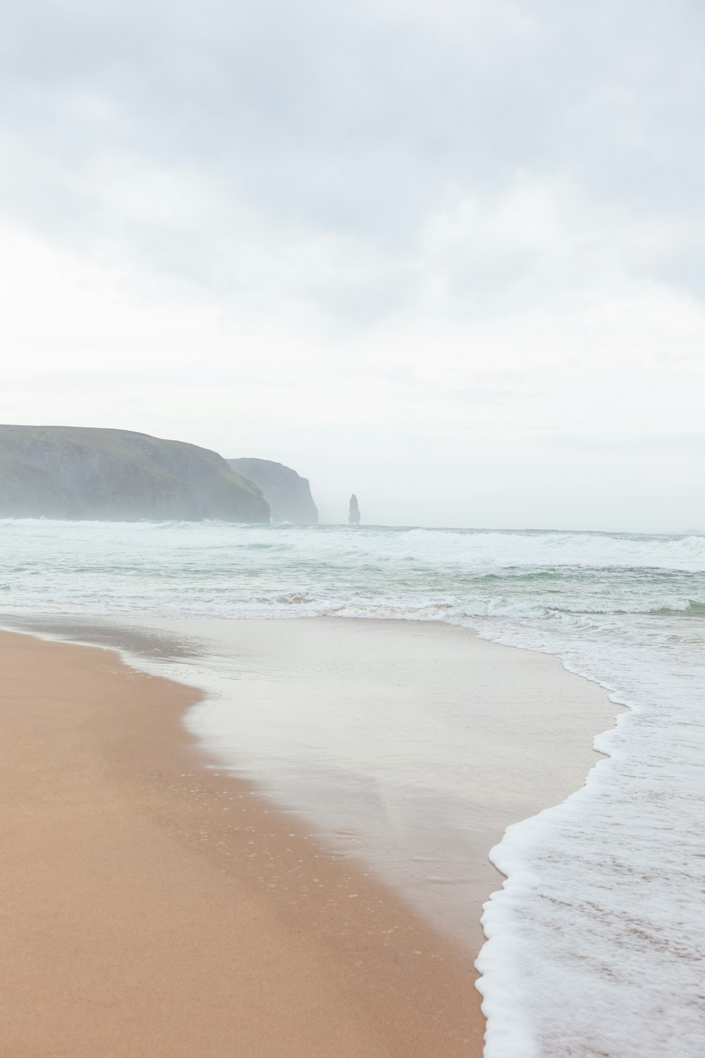 a sandy beach with waves coming in to shore