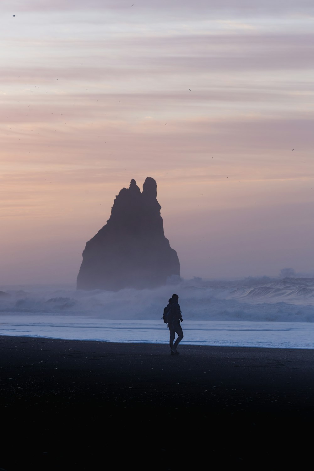 a person walking on a beach near the ocean