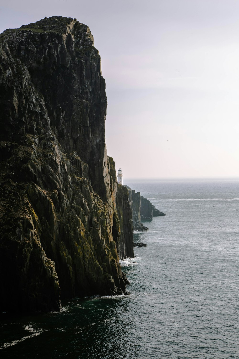 a rocky cliff with a lighthouse on top of it