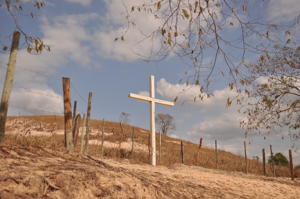 a wooden cross sitting on top of a dirt hill
