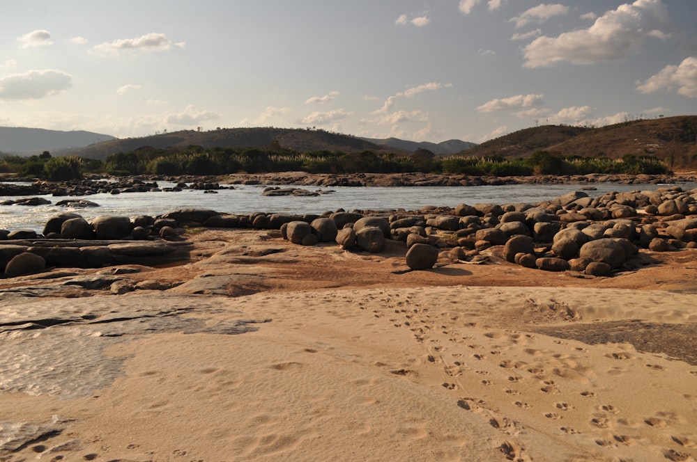 a sandy beach with rocks and a body of water