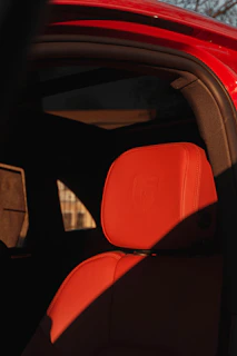 Close-up of the Noirluxe logo embossed subtly on a dark leather headrest inside the car.