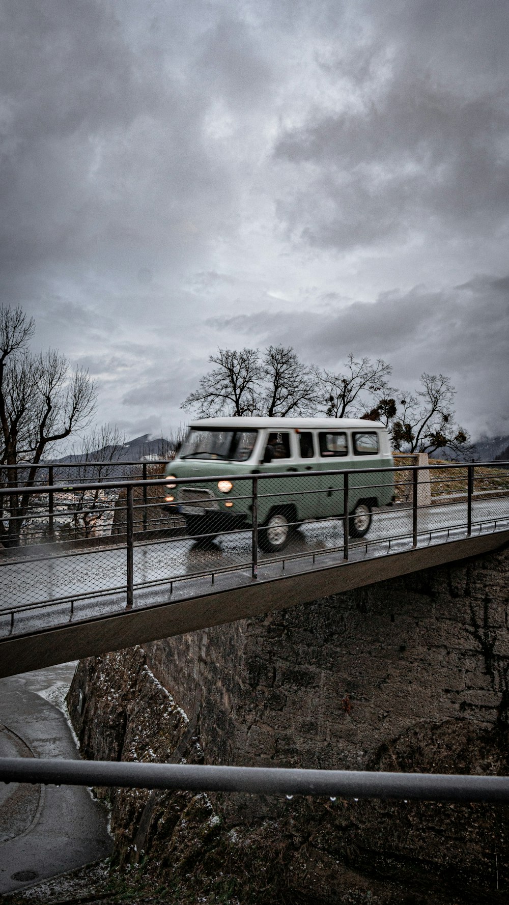 a van driving over a bridge on a cloudy day