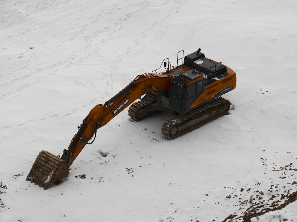 an orange and black bulldozer digging in the snow