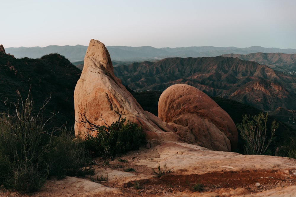 a large rock sitting on top of a lush green hillside