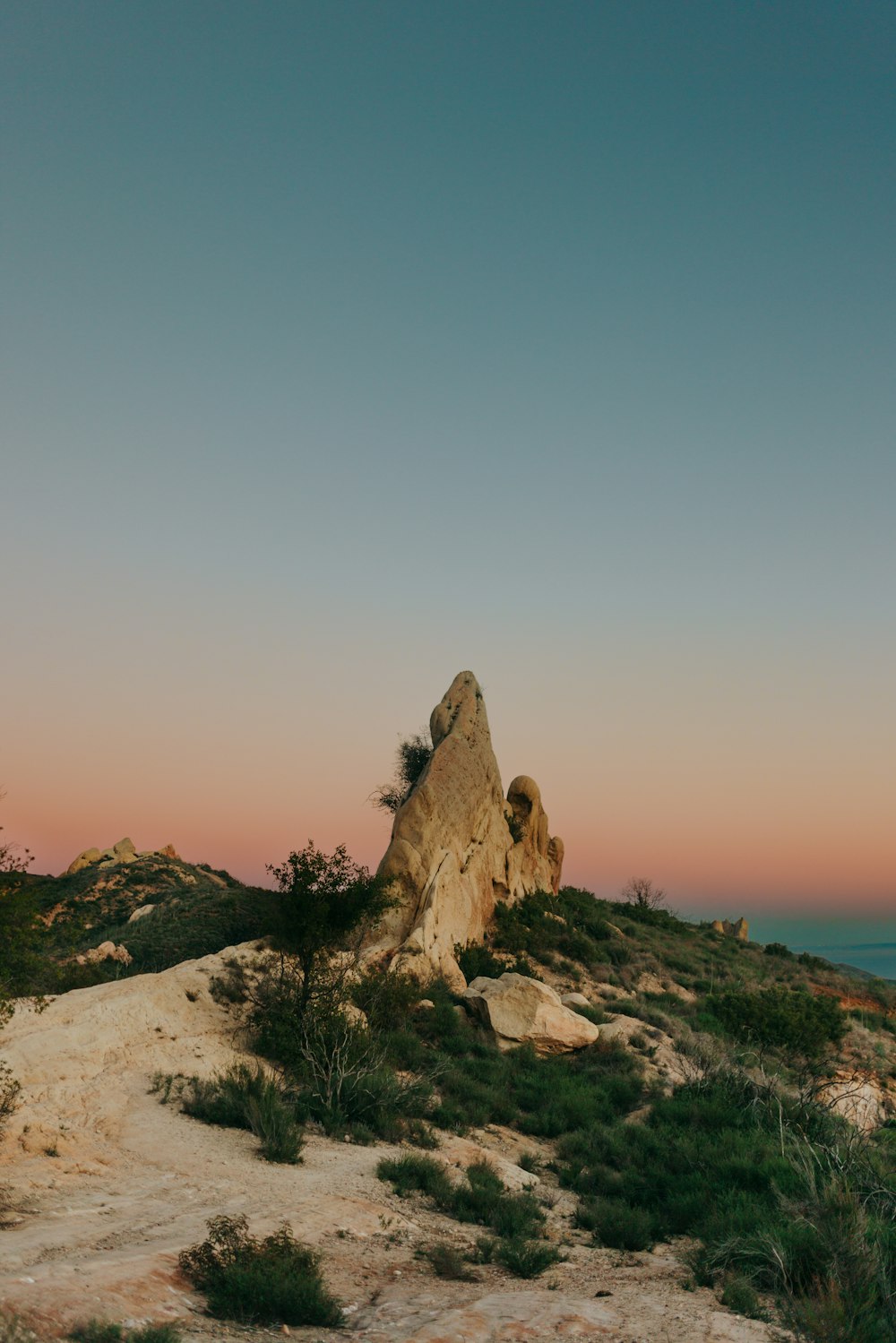 a large rock sitting on top of a lush green hillside