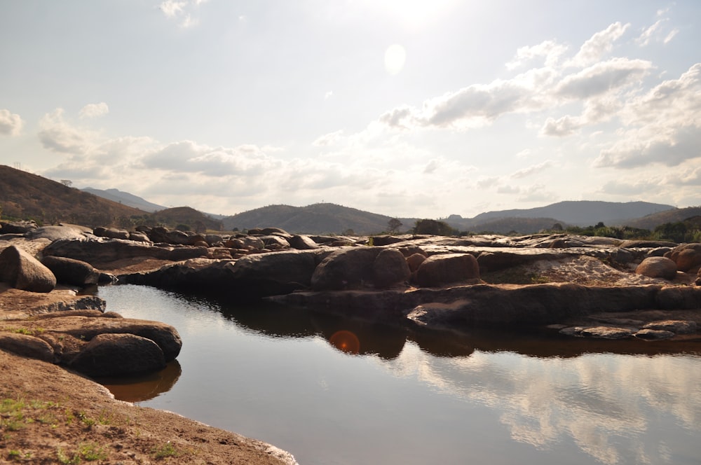 a body of water surrounded by rocks and grass