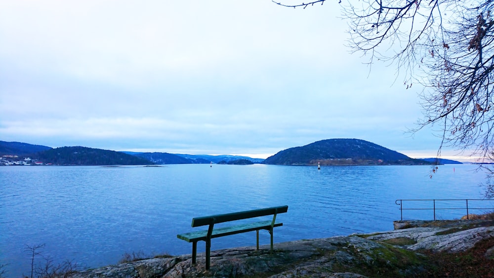 a bench sitting on the shore of a lake