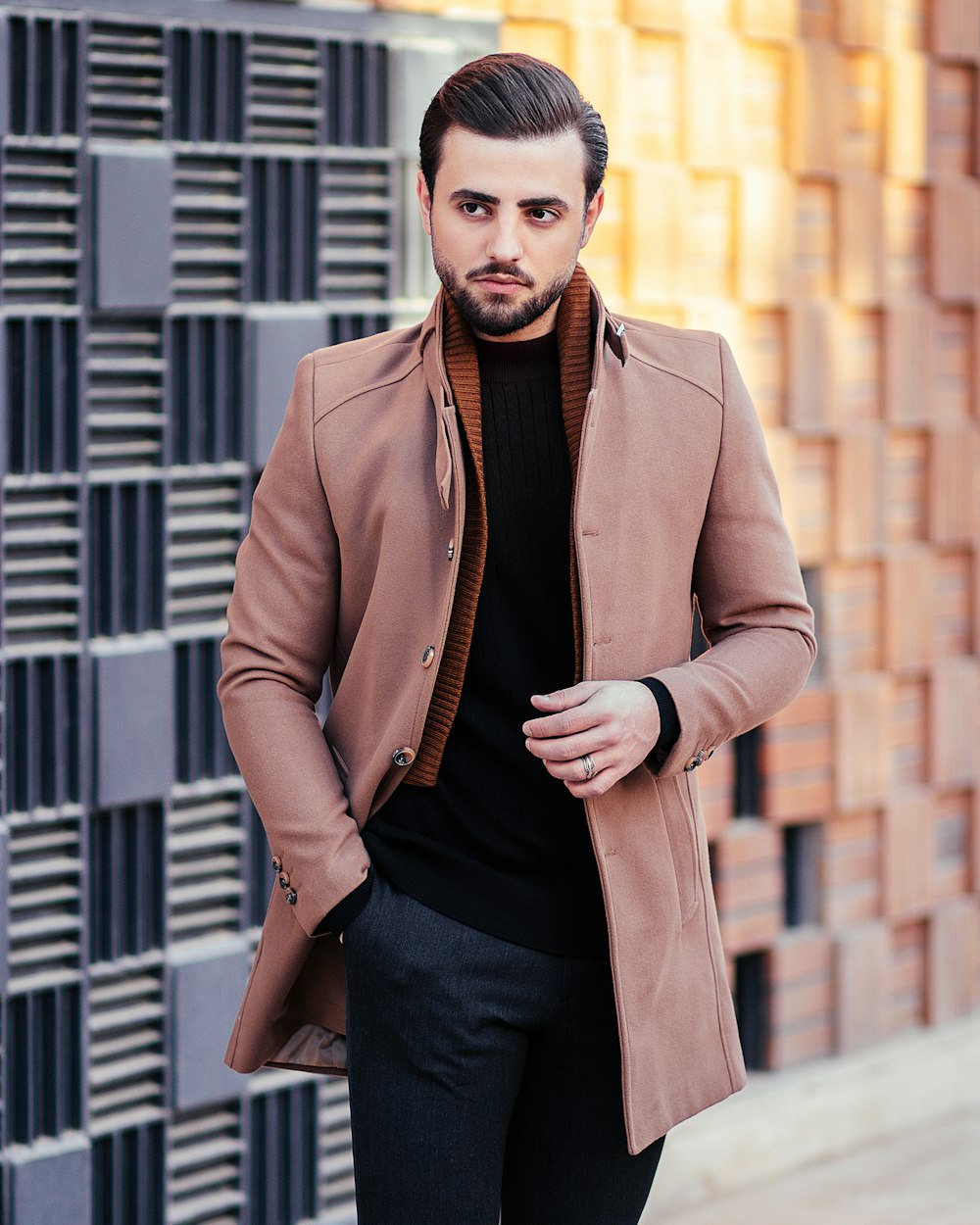 a man standing in front of a building wearing a brown coat