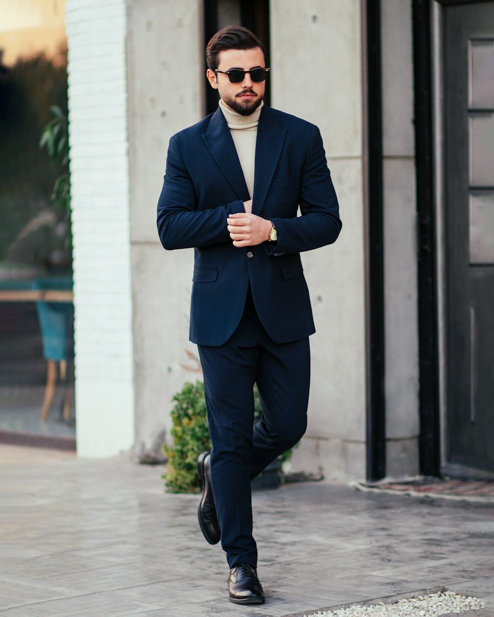 a man in a suit and sunglasses is walking down the street
