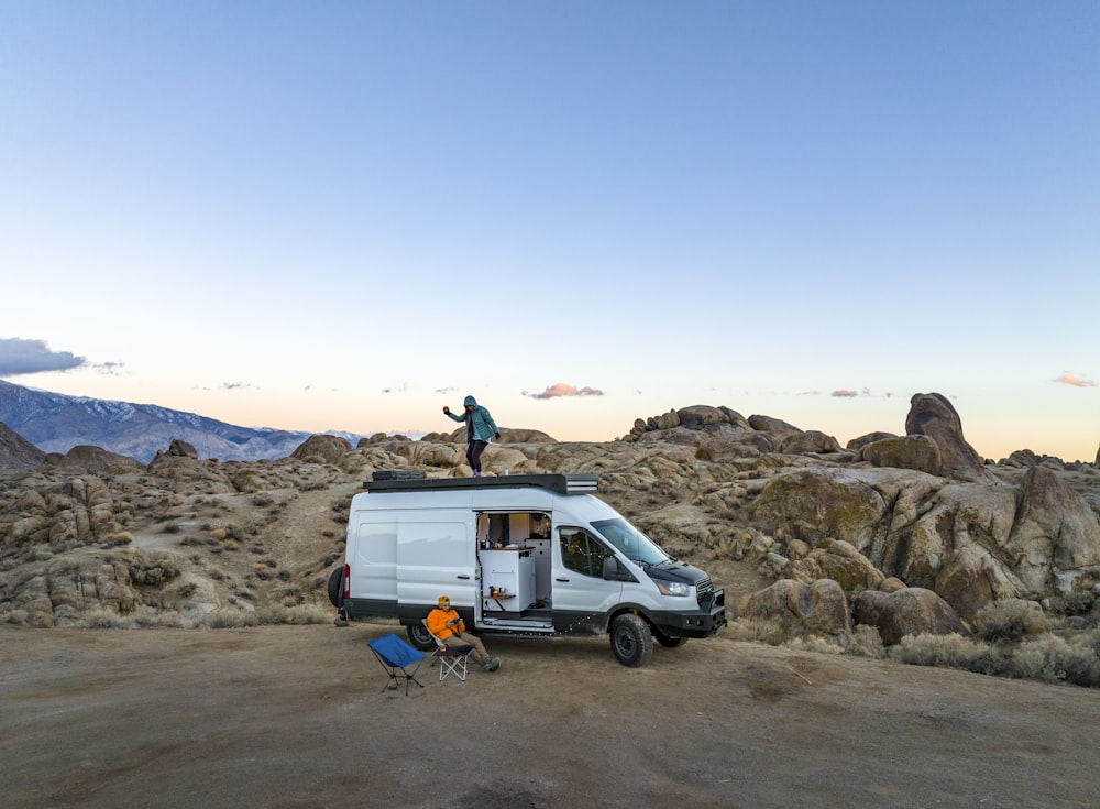 a man standing on top of a van in the desert