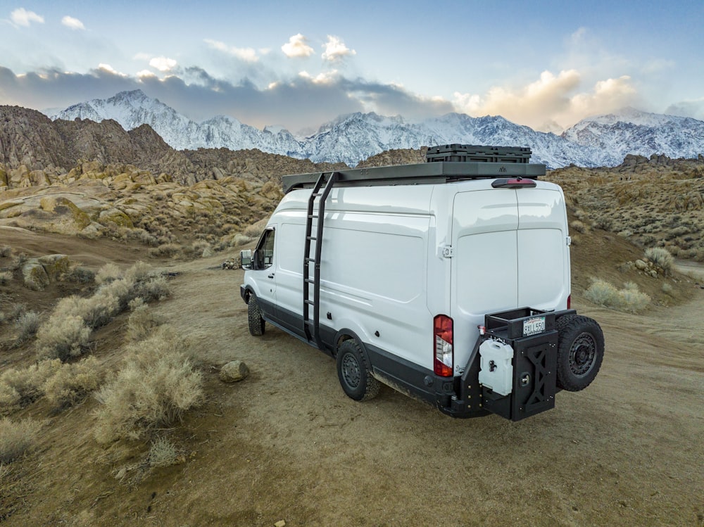 a white van parked in the desert with mountains in the background