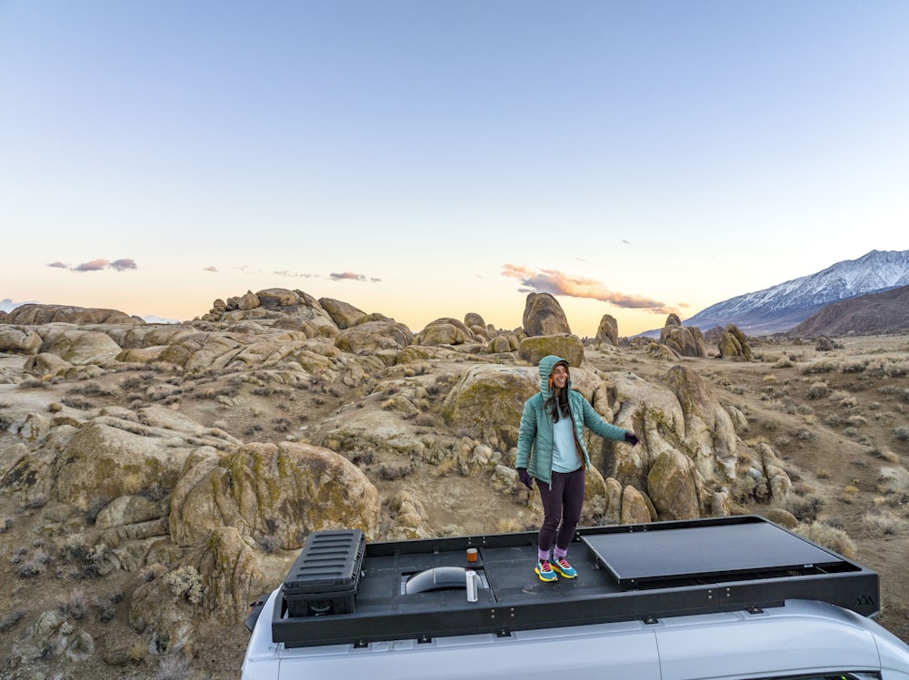 a woman standing on top of a car in the desert