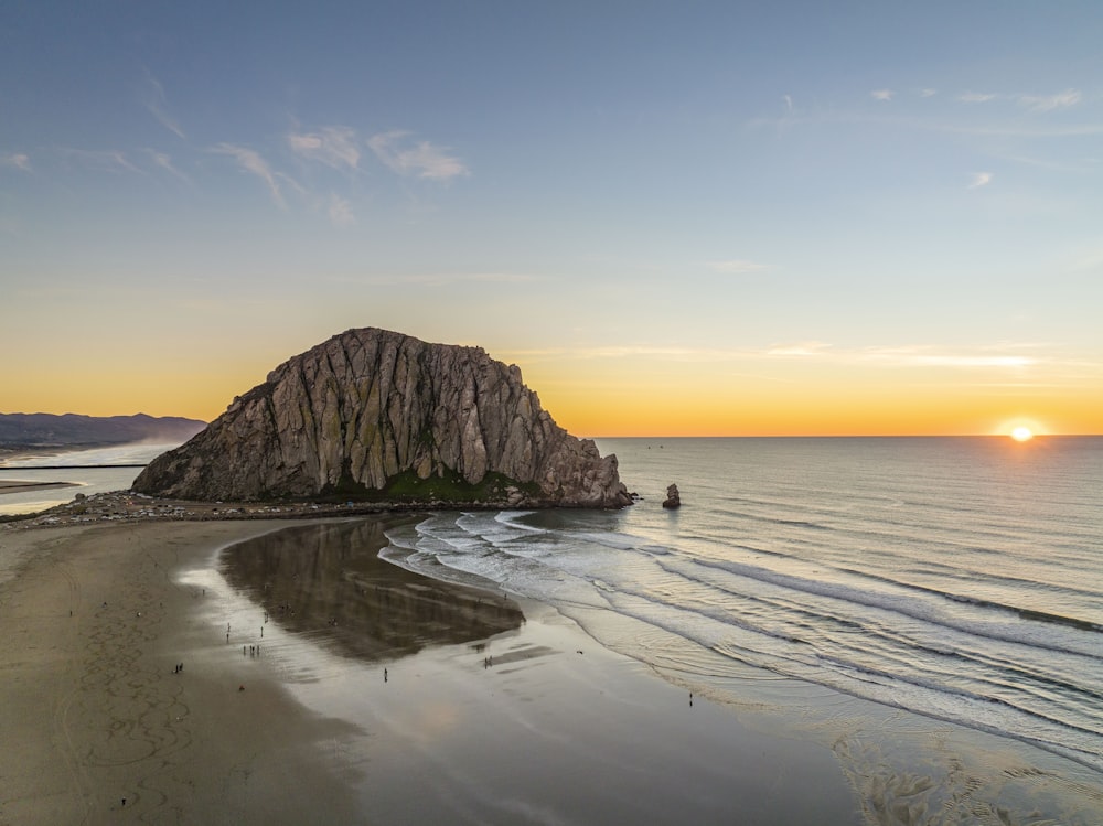 a large rock sitting on top of a beach next to the ocean