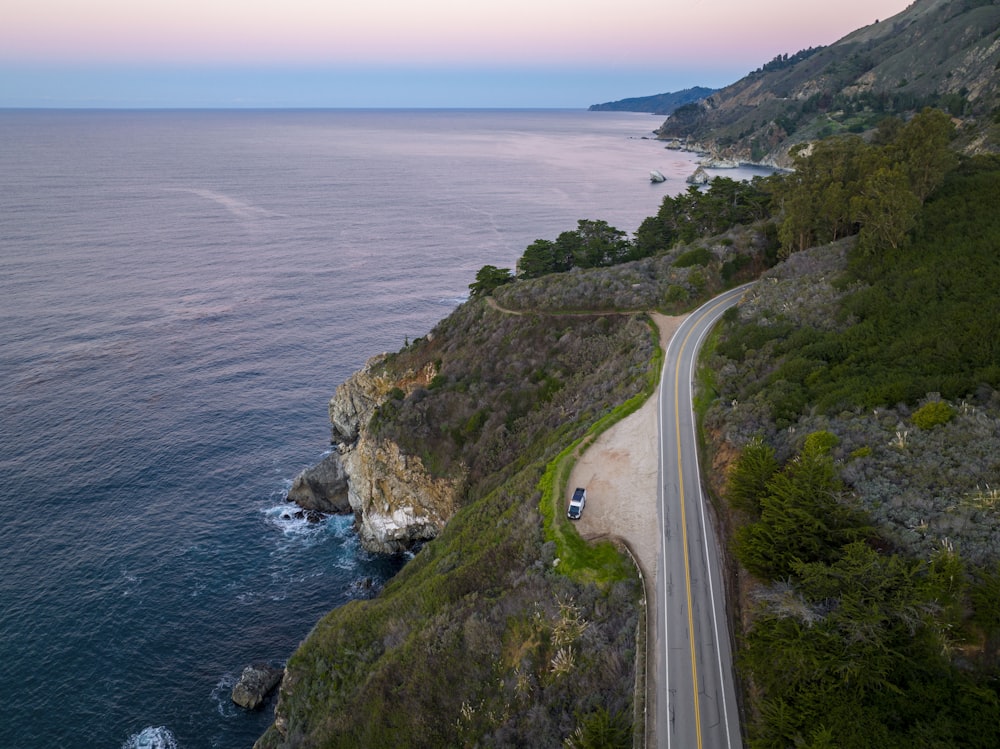 a car driving down a road next to the ocean