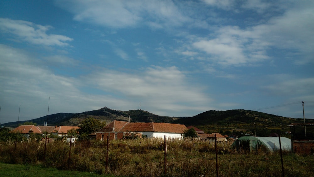 uma casa no meio de um campo com montanhas ao fundo