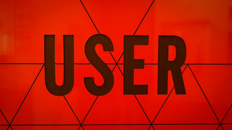 Bold, black typography spells the word 'USER' against a vibrant orange background with geometric triangular patterns.