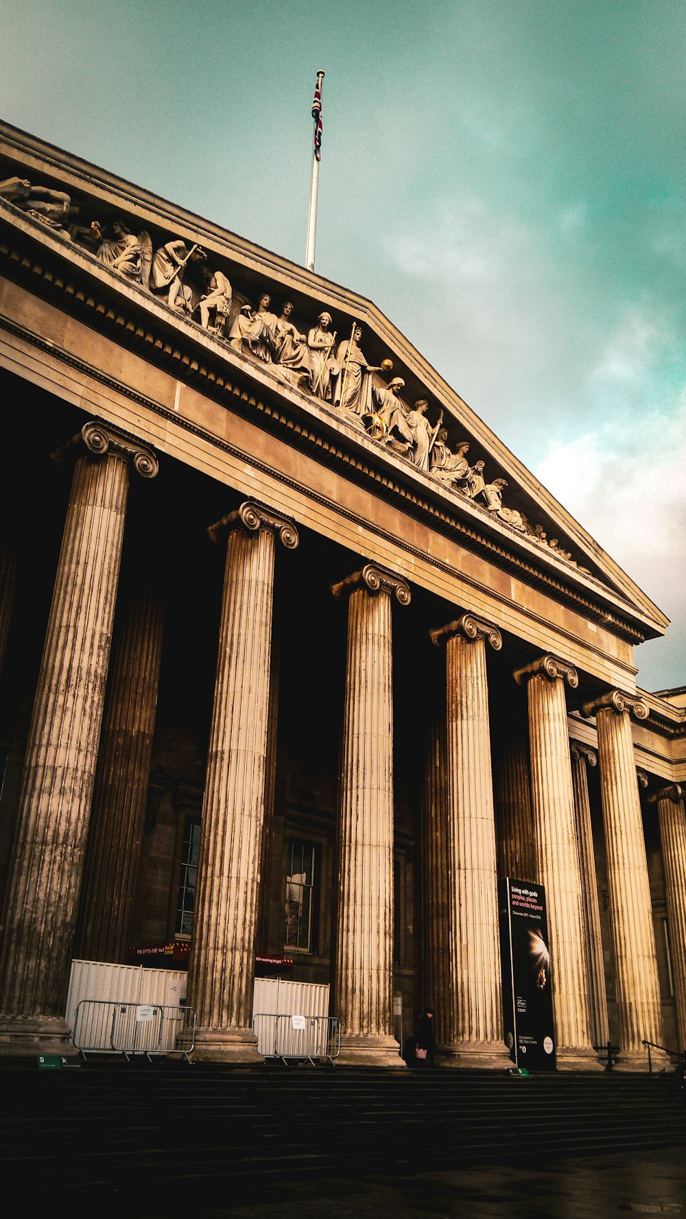 a tall building with columns and a flag on top of it