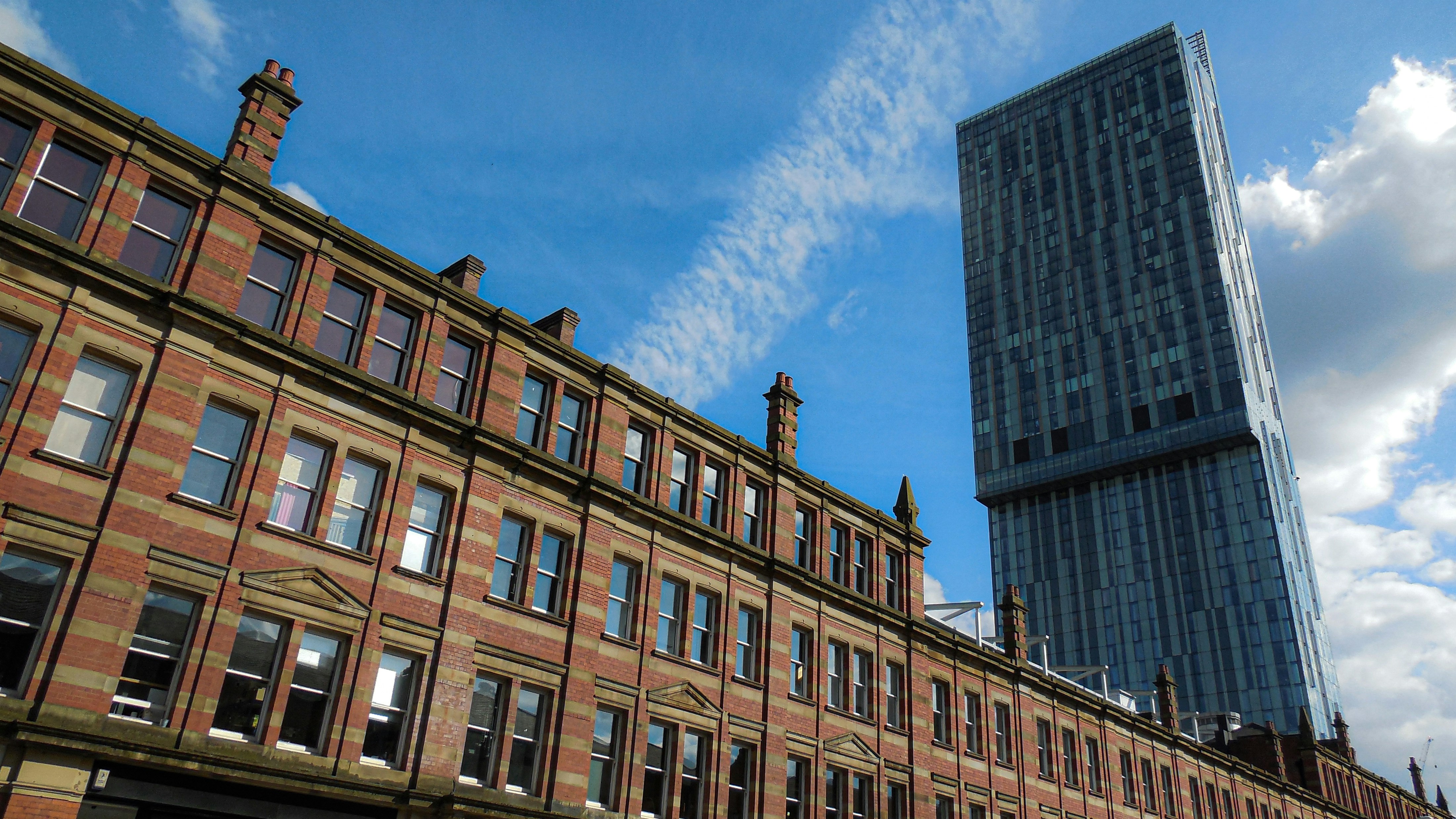 Street view photo looking up to a modern high rise hotel building (Hilton Hotel in Deansgate, Manchester). Photograph by Mark Stuckey.