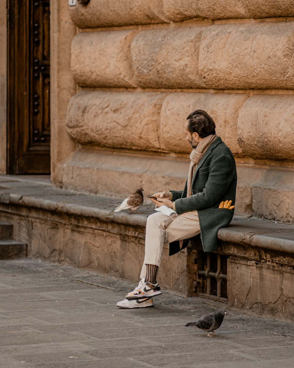 a man sitting on a bench next to a bird