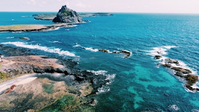 an aerial view of the ocean with a small island in the distance