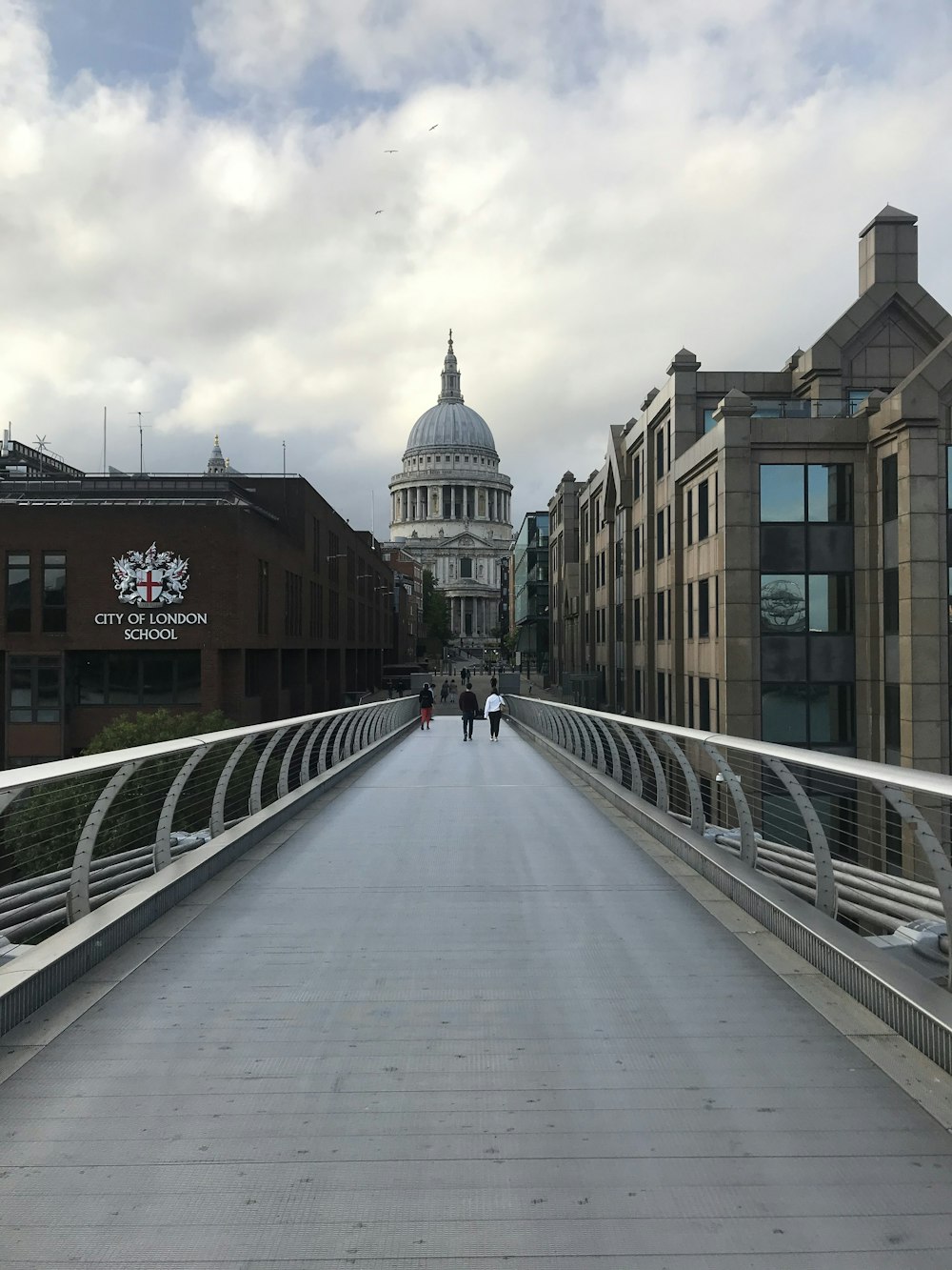 two people walking across a bridge in a city